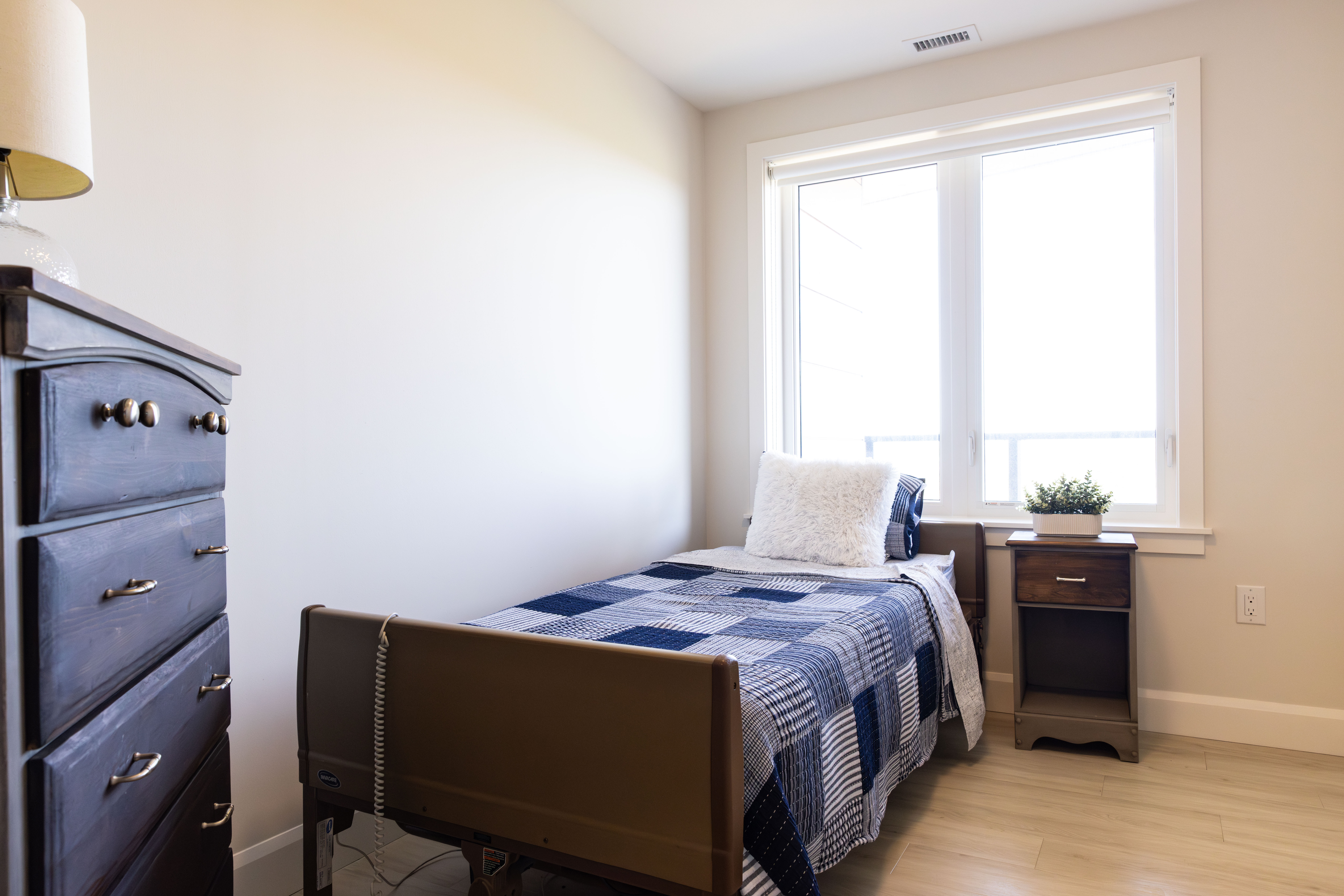Private suite bedroom with adjustable bed, natural light, and homelike furnishings at Laurels Lake.